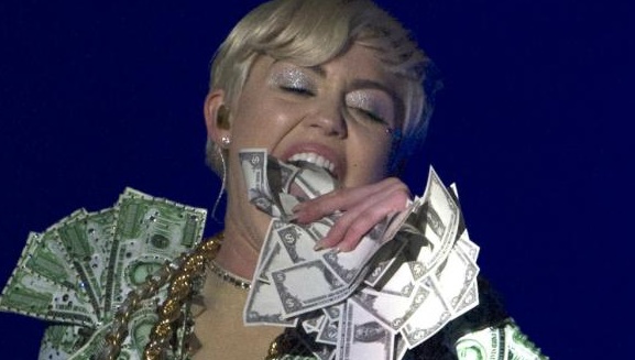 Miley Cyrus si spoglia e mangia soldi sul palco